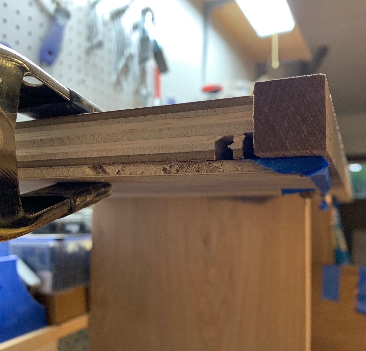 side view of the top piece with the edging clamped to it and a scrap piece of wood holding it flush on the bottom